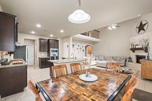 21735 Lozar Dr, Spring, TX 77379 - dining area featuring visible vents, a stone fireplace, arched walkways, a ceiling fan, and light tile patterned floors