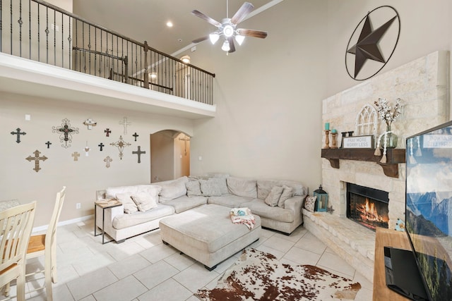 21735 Lozar Dr, Spring, TX 77379 - living area featuring ceiling fan, a stone fireplace, a towering ceiling, arched walkways, and tile patterned floors
