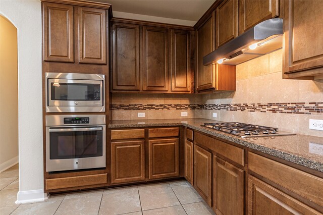 2623 Holbrook Springs Ln, League City, TX 77573 - kitchen with arched walkways, decorative backsplash, stainless steel appliances, and under cabinet range hood