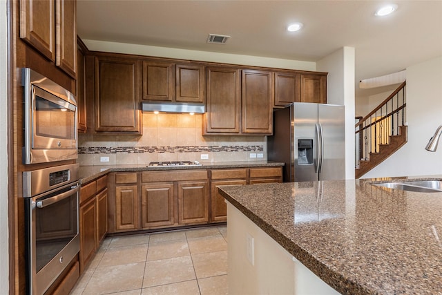 2623 Holbrook Springs Ln, League City, TX 77573 - kitchen with a sink, decorative backsplash, under cabinet range hood, dark stone countertops, and appliances with stainless steel finishes
