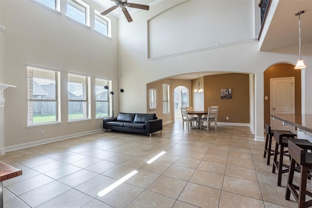 2623 Holbrook Springs Ln, League City, TX 77573 - living room with baseboards, arched walkways, light tile patterned flooring, ceiling fan with notable chandelier, and a high ceiling