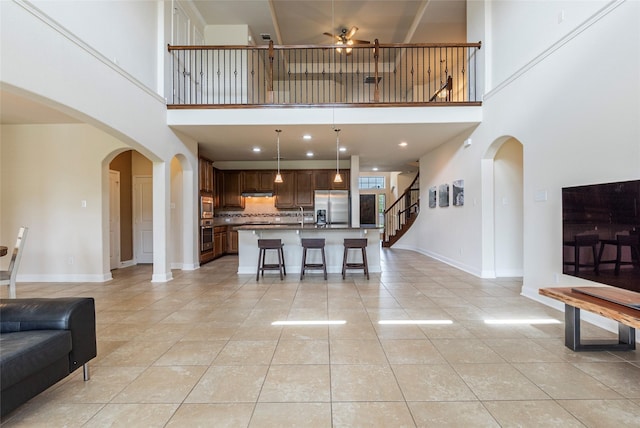 2623 Holbrook Springs Ln, League City, TX 77573 - living room with light tile patterned floors, baseboards, arched walkways, a towering ceiling, and a ceiling fan