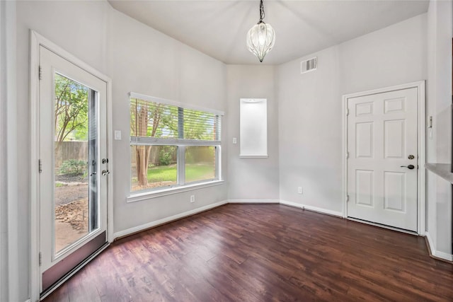 spare room with healthy amount of natural light, dark wood-style floors, a chandelier, and baseboards