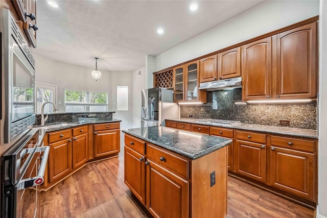 kitchen featuring under cabinet range hood, appliances with stainless steel finishes, light wood-type flooring, backsplash, and recessed lighting