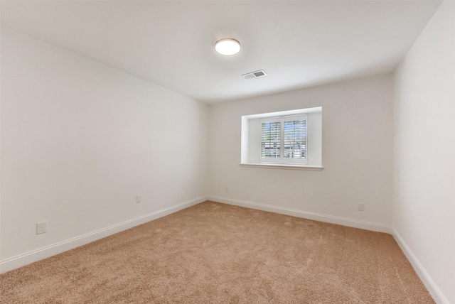 empty room with visible vents, light colored carpet, and baseboards