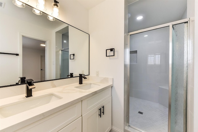 bathroom with double vanity, a sink, a shower stall, and visible vents