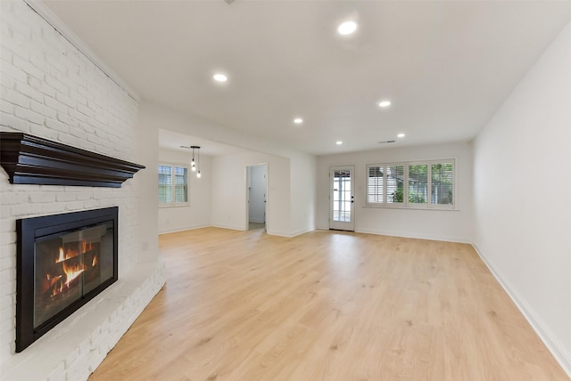 unfurnished living room featuring a brick fireplace, recessed lighting, light wood finished floors, and baseboards