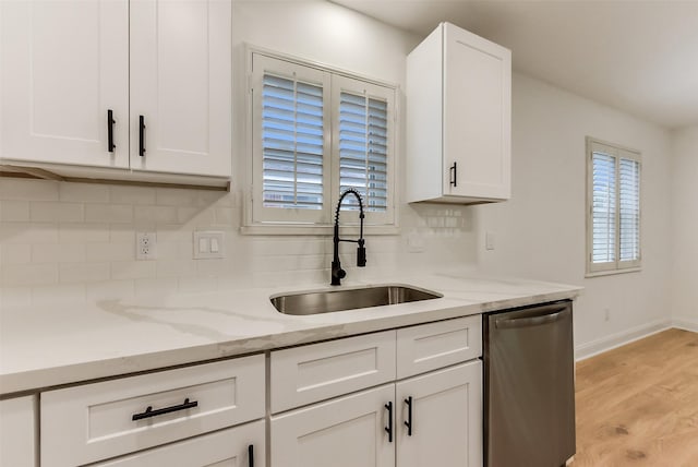 kitchen with decorative backsplash, dishwasher, white cabinets, and a sink