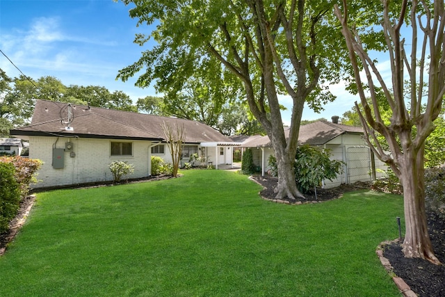 back of property with brick siding, fence, a shingled roof, and a yard