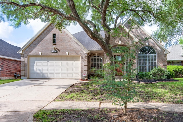 view of front of property with driveway, a shingled roof, brick siding, and a garage