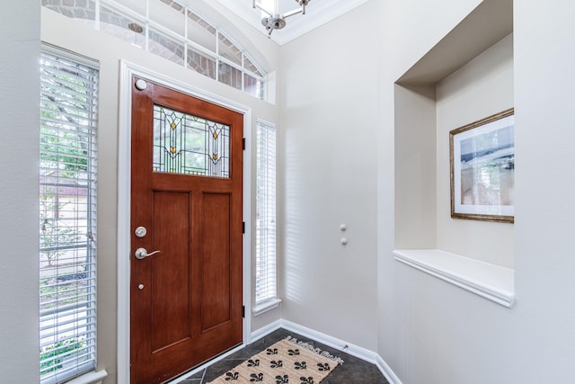 foyer featuring a wealth of natural light, crown molding, and baseboards