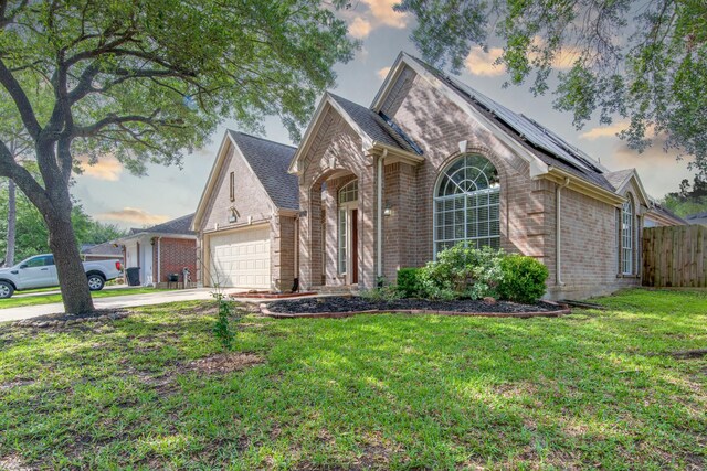 view of front facade featuring brick siding, fence, a garage, a front lawn, and concrete driveway