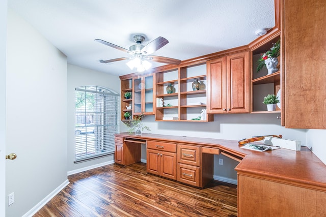 home office featuring a ceiling fan, built in study area, dark wood-style flooring, and baseboards