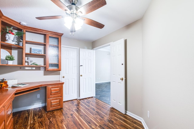 unfurnished office featuring baseboards, a ceiling fan, and built in study area