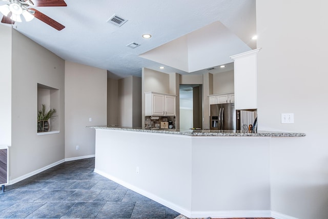 kitchen featuring visible vents, ceiling fan, light stone counters, and stainless steel fridge with ice dispenser