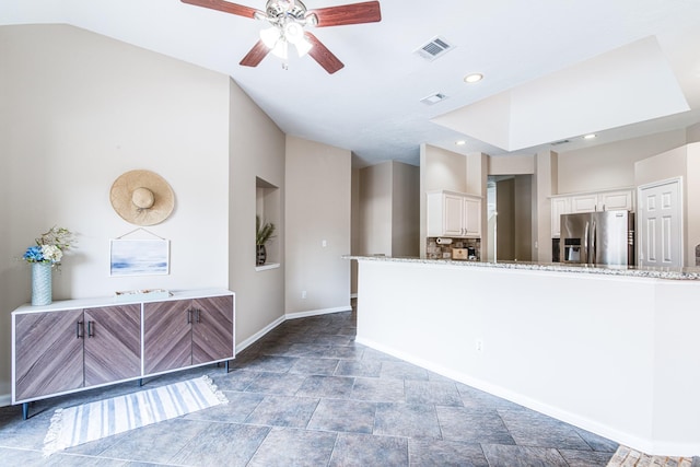 interior space featuring stone finish flooring, visible vents, baseboards, vaulted ceiling, and a ceiling fan