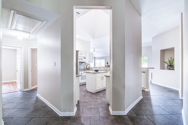 hallway with baseboards, attic access, and stone tile flooring