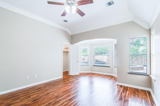 empty room with wood finished floors, visible vents, ceiling fan, and arched walkways