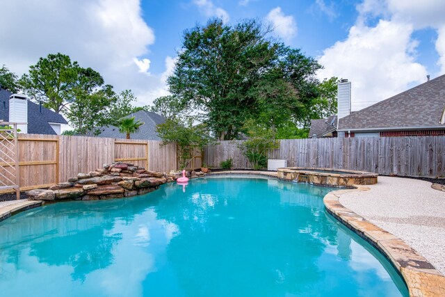 view of pool featuring a fenced backyard and a pool with connected hot tub
