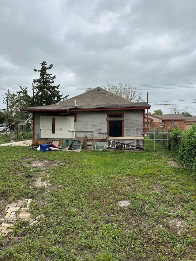 rear view of property featuring a yard and fence