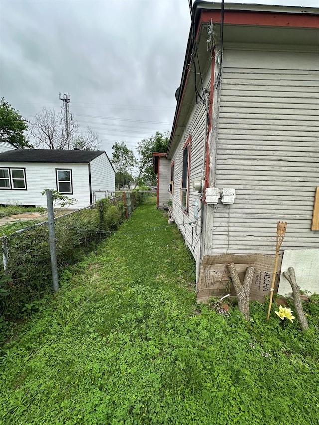 view of side of property featuring fence and a lawn
