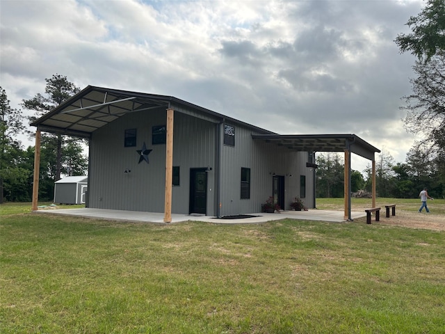 rear view of property with a lawn, a carport, and an outbuilding