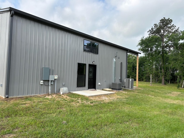 rear view of property with cooling unit, a yard, and board and batten siding