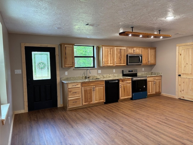 kitchen featuring stainless steel microwave, a sink, electric range, black dishwasher, and wood finished floors