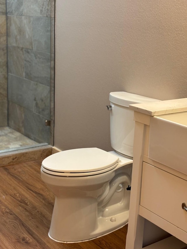 bathroom with wood finished floors, toilet, a shower stall, and vanity
