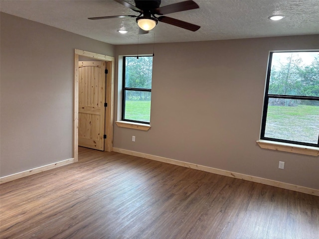 empty room featuring baseboards, wood finished floors, a ceiling fan, and a wealth of natural light