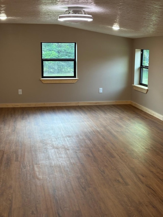 spare room with a textured ceiling, wood finished floors, and baseboards