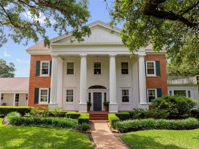 neoclassical / greek revival house with a front yard and brick siding