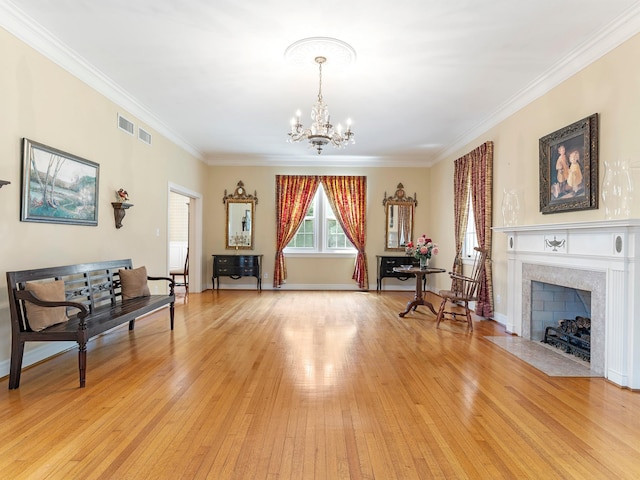 sitting room with visible vents, a high end fireplace, an inviting chandelier, light wood-type flooring, and ornamental molding
