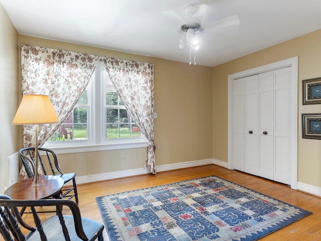 living area featuring wood finished floors, ceiling fan, and baseboards