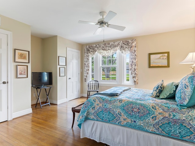 bedroom featuring baseboards, wood finished floors, and a ceiling fan