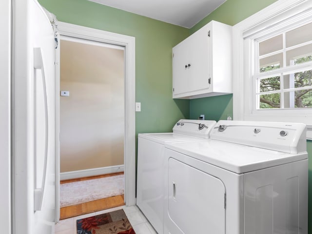 laundry area with light tile patterned floors, separate washer and dryer, cabinet space, and baseboards