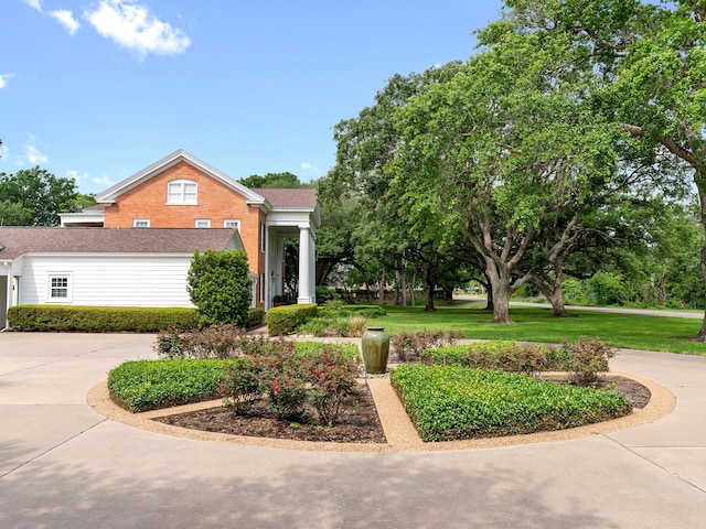 view of front facade with brick siding, a front lawn, concrete driveway, and roof with shingles