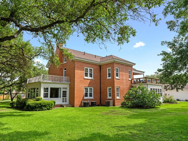 back of house with a lawn, a chimney, a balcony, and entry steps