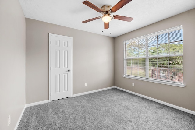 carpeted empty room featuring a ceiling fan and baseboards