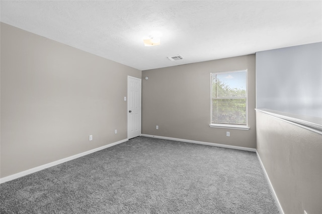 carpeted empty room with a textured ceiling, visible vents, and baseboards