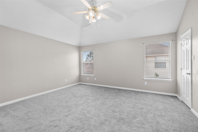 carpeted empty room featuring ceiling fan, vaulted ceiling, and baseboards