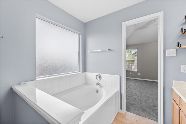 bathroom with a garden tub, vanity, tile patterned floors, and baseboards