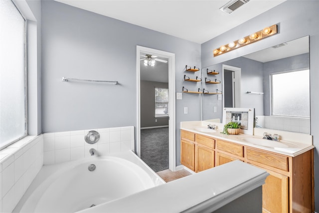 bathroom with a bath, double vanity, a sink, and visible vents