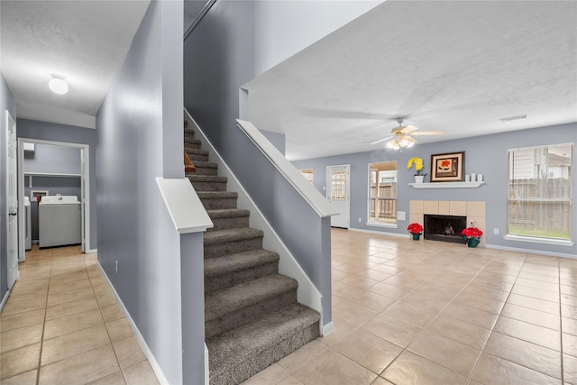stairway featuring washer / dryer, a ceiling fan, a textured ceiling, tile patterned flooring, and plenty of natural light