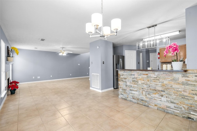 interior space with stainless steel fridge, light tile patterned flooring, visible vents, pendant lighting, and ceiling fan with notable chandelier