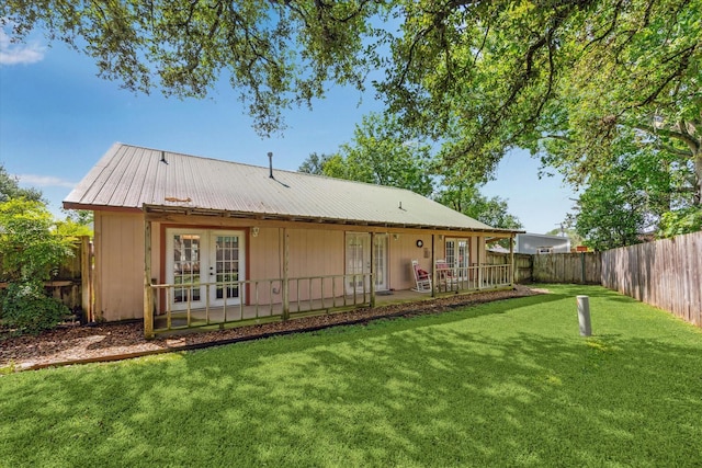 back of property with french doors, a fenced backyard, metal roof, and a yard