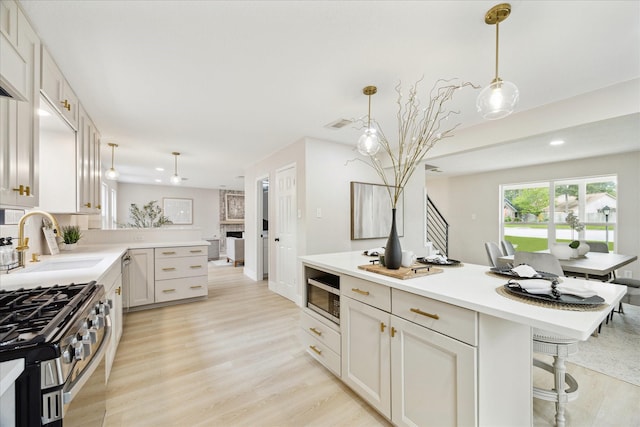 kitchen featuring light countertops, decorative light fixtures, a sink, and light wood finished floors
