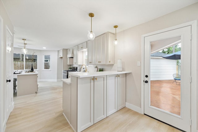 kitchen with stainless steel range with gas cooktop, light wood finished floors, a peninsula, and custom exhaust hood