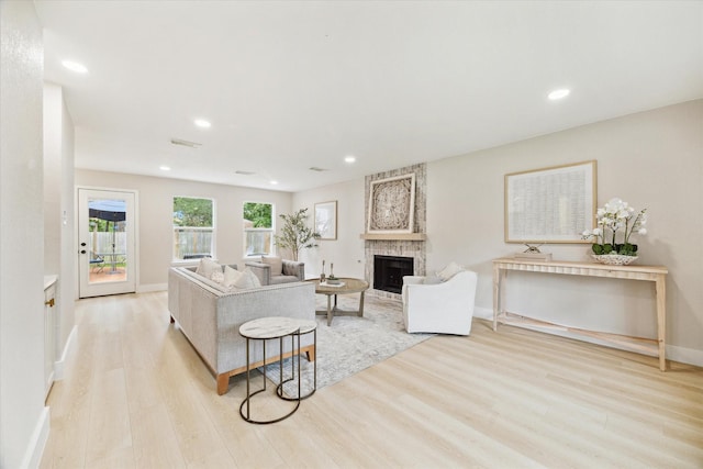 living area featuring recessed lighting, baseboards, a large fireplace, and light wood-style flooring