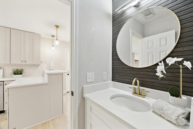bathroom with vanity, a textured wall, and wood finished floors